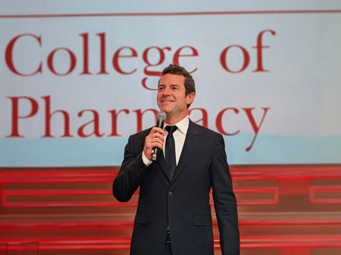 Joe Cummings delivering a keynote presentation in a suit with a microphone at a corporate conference